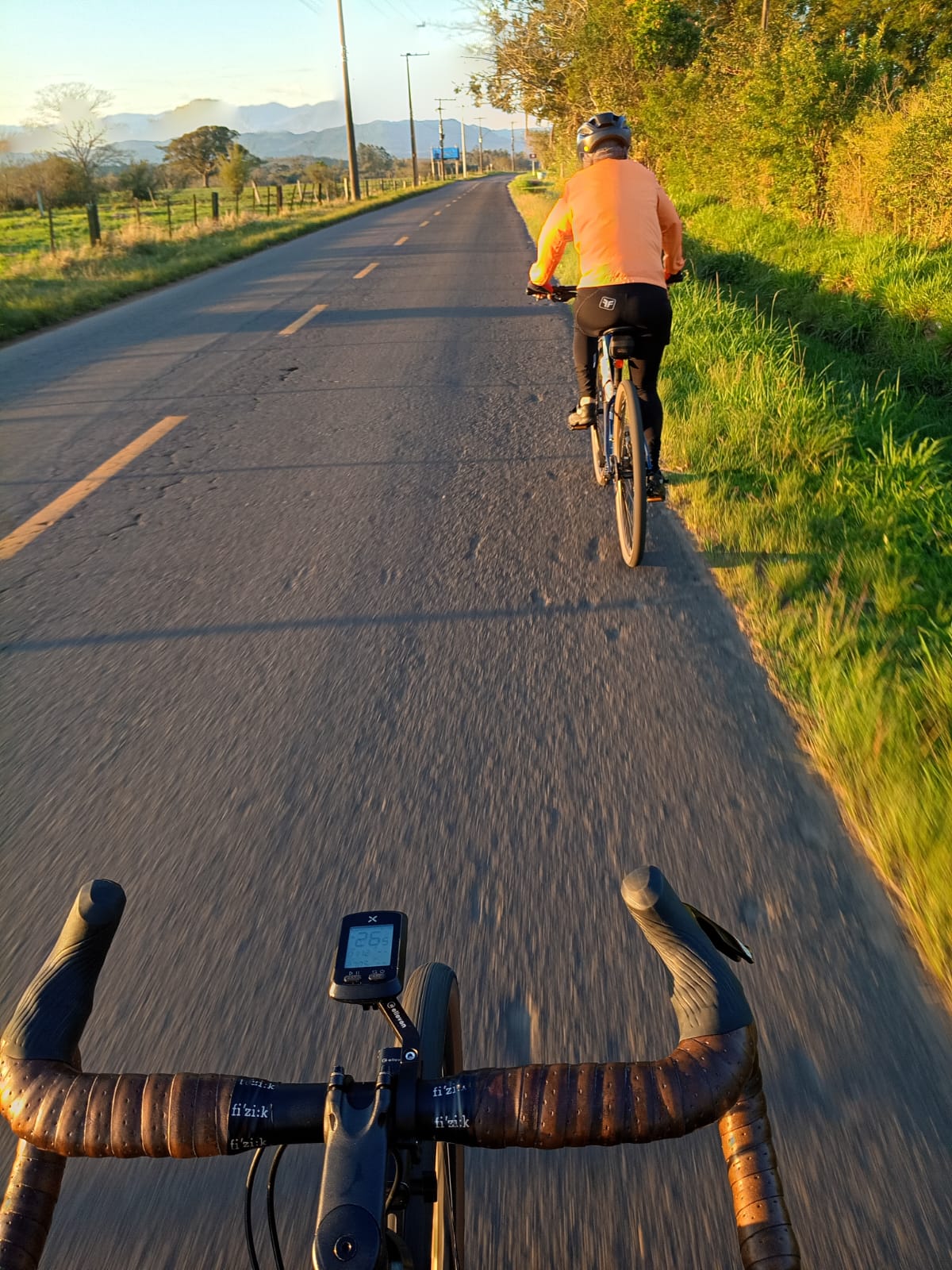 Ciclistas pedalando em estrada rural na luz do amanhecer