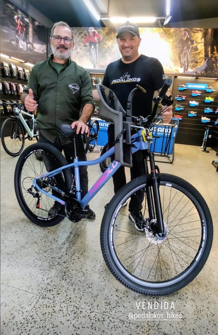Cliente retirando e-bike laranja com acessórios na Pedalokos