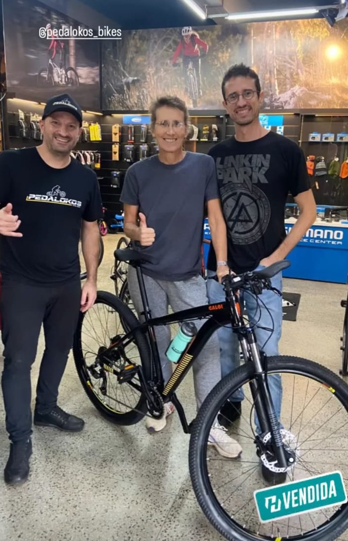 Família recebendo mountain bike Caloi preta após consultoria de compra