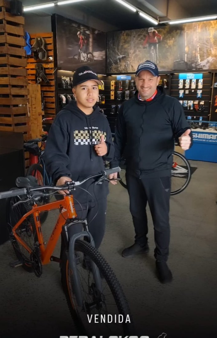 Jovem cliente com mountain bike laranja escolhida para começar a pedalar