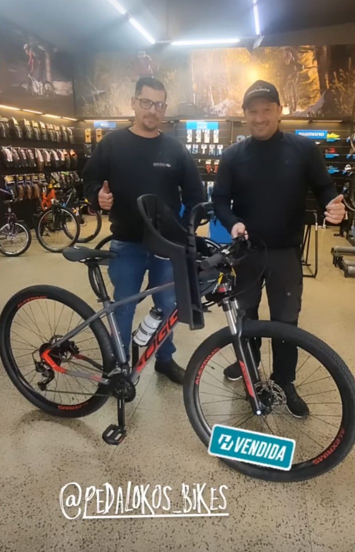Cliente com bicicleta Oggi cinza equipada com cadeirinha para levar a criança