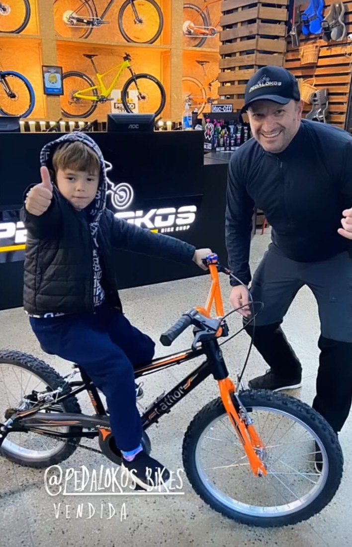 Criança com sua primeira bicicleta aro 20 laranja escolhida na loja