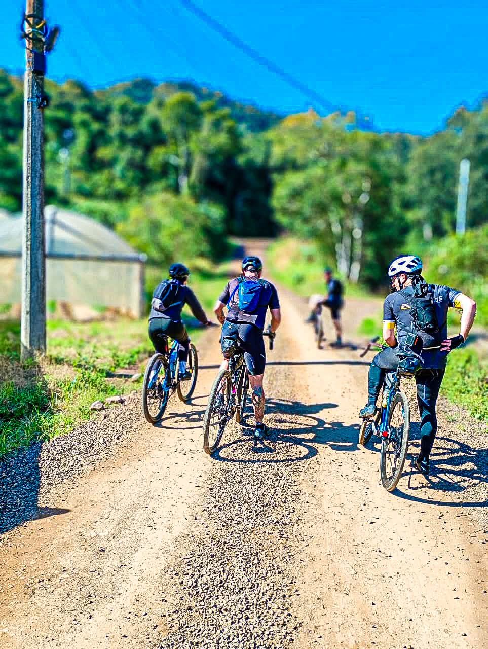 Grupo de ciclistas pedalando em estrada de chão