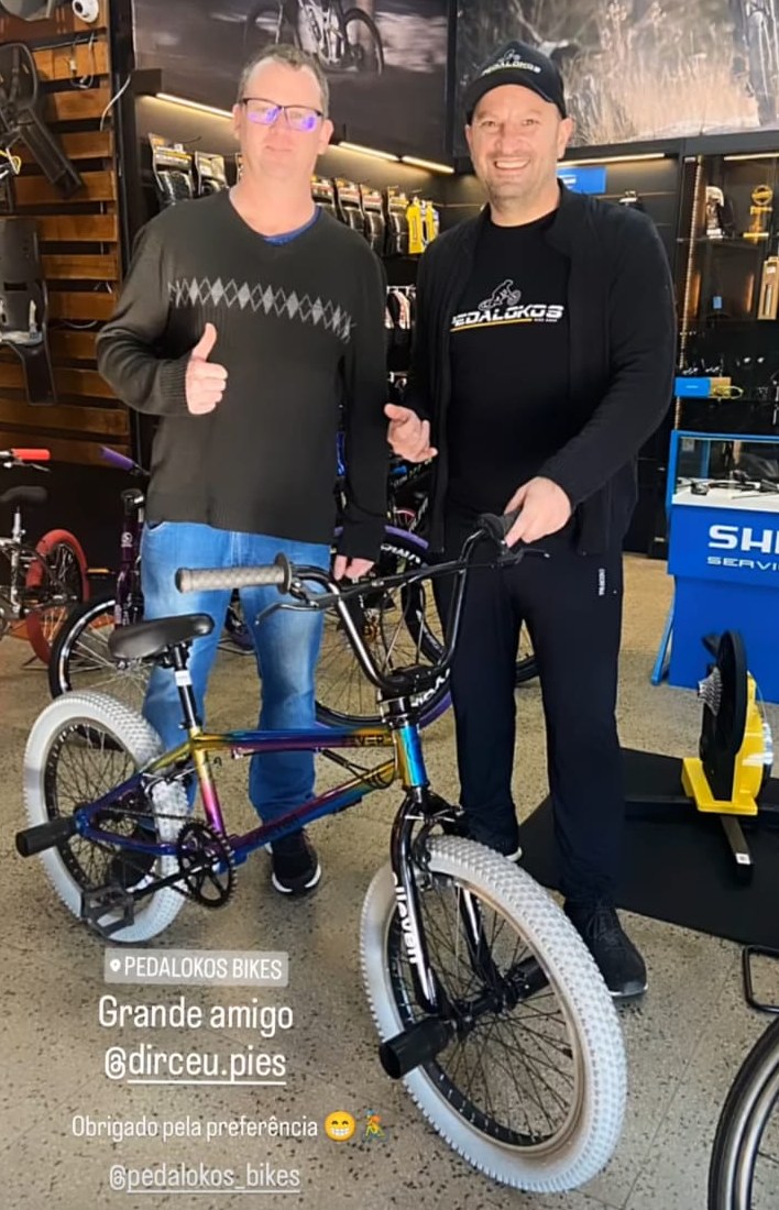 Cliente recebendo bicicleta aro 20 com quadro colorido após atendimento