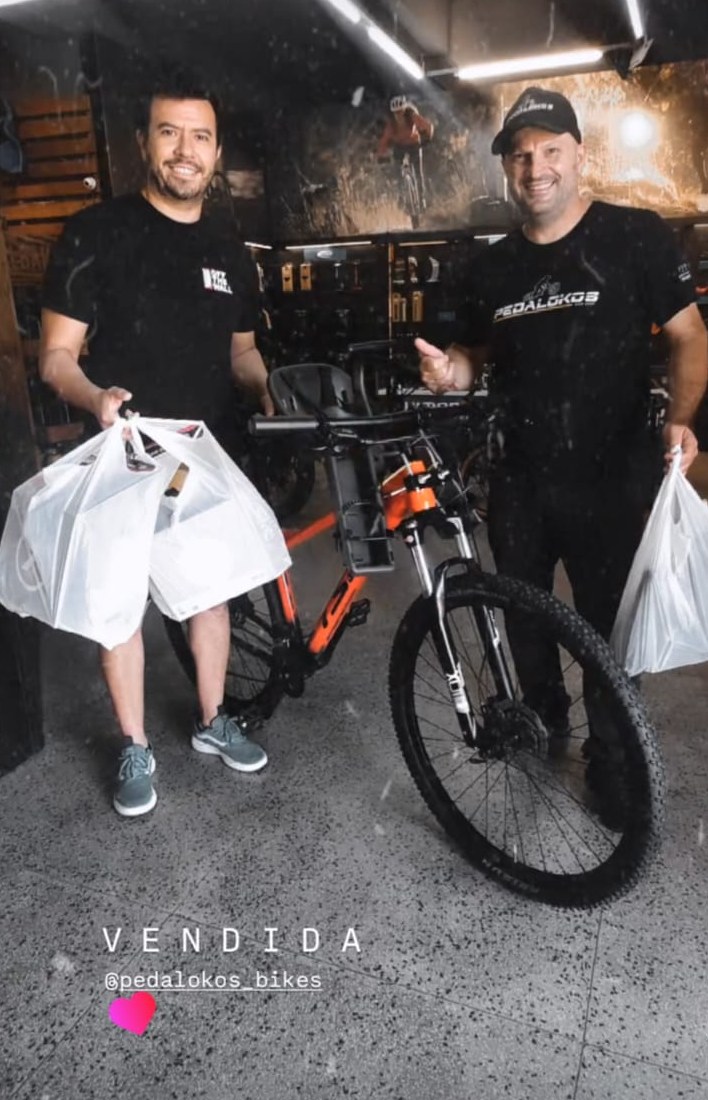 Cliente com bicicleta azul equipada com cadeirinha infantil para passeios em família